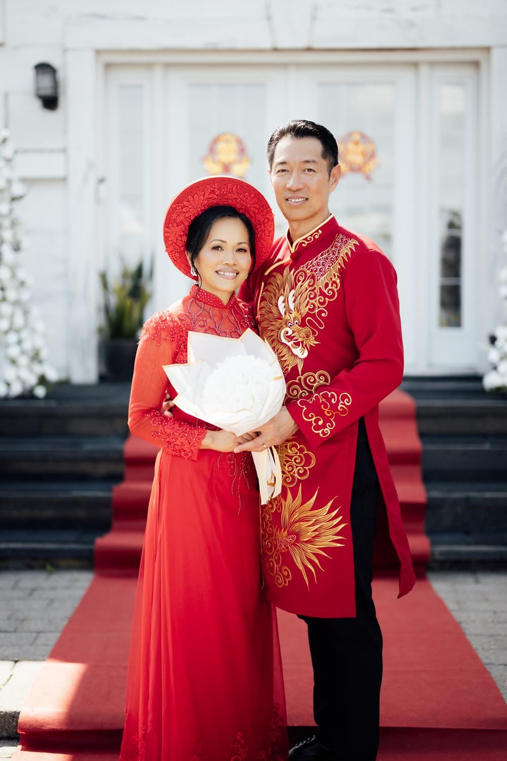 Mariage traditionnel vietnamien : les mariés en áo dài rouge et or devant le tapis rouge