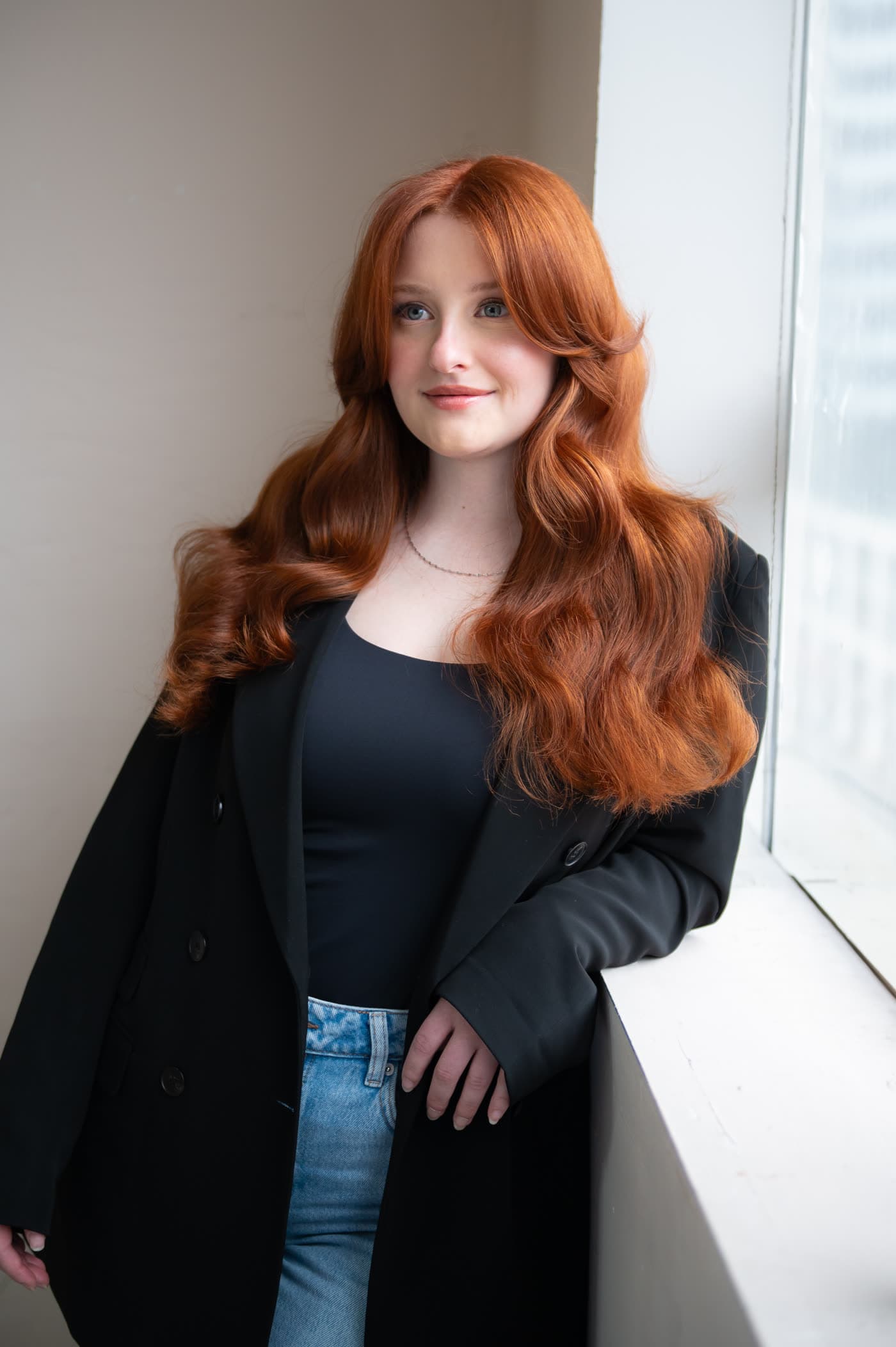 Window-light portrait: auburn hair, black blazer, luminous natural makeup and a rosy lip
