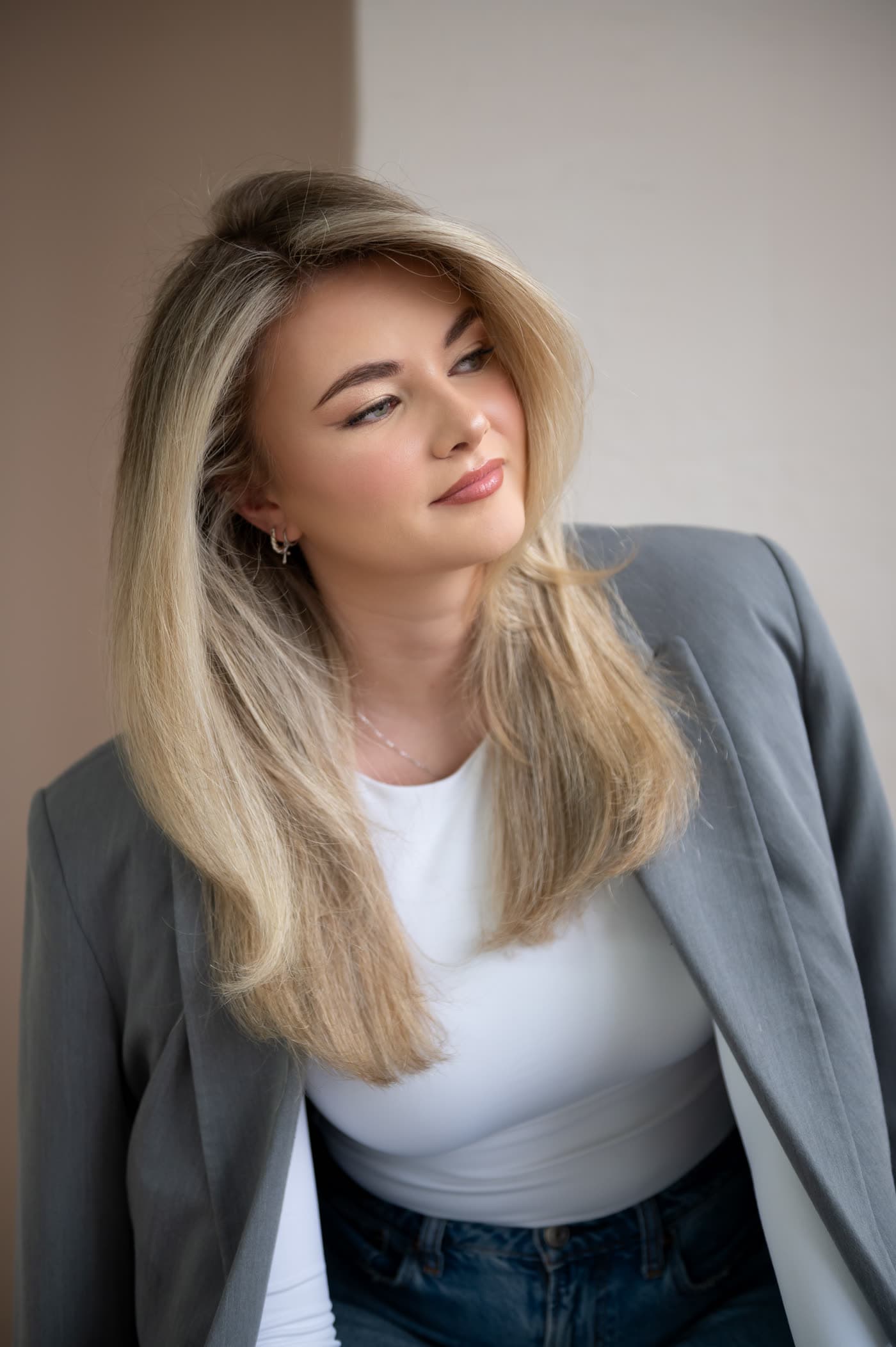 Natural-light portrait: blonde in a grey blazer, soft glam with a winged liner and luminous skin